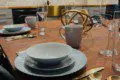 Close-up of a stylishly set wooden dining table with gold utensils and modern dishware in a Fairbanks Alaska treehouse
