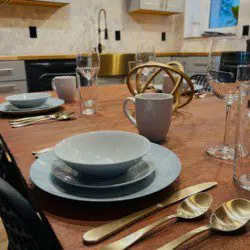 Close-up of a stylishly set wooden dining table with gold utensils and modern dishware in a Fairbanks Alaska treehouse