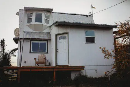 Small white house with front deck and chairs in Fairbanks, Alaska—ideal for treehouse-style rental or lodge getaway