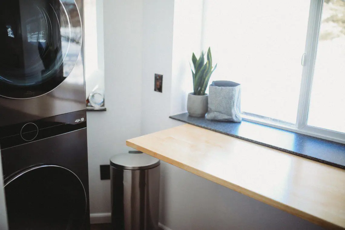 Sunny laundry area with potted plant and trash bin in Fairbanks treehouse rental