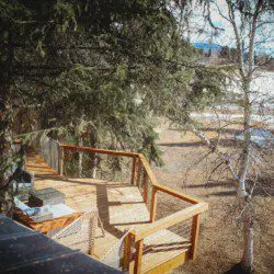Wooden deck with chairs nestled among trees overlooking a quiet forested landscape in Fairbanks, Alaska