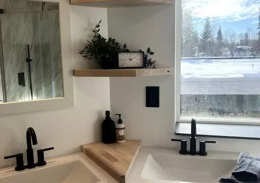 Glass-enclosed shower with marble-style tile in a modern Fairbanks treehouse bathroom