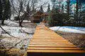 Wooden path through snow leading to rustic treehouse cabins in Fairbanks Alaska