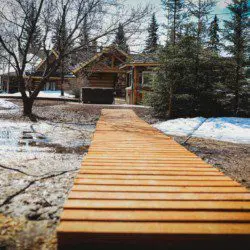 Wooden path through snow leading to rustic treehouse cabins in Fairbanks Alaska