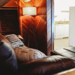 Cozy leather seating and warm wood interior of a Fairbanks treehouse rental with view into a small kitchen
