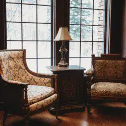 Vintage-style armchairs and side table near large window with snowy view in a Fairbanks Alaska lodge