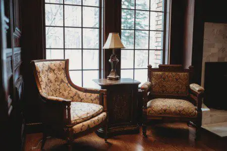 Vintage-style armchairs and side table near large window with snowy view in a Fairbanks Alaska lodge