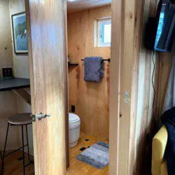 Compact modern bathroom with dual sinks, wood shelves, and black fixtures in Fairbanks Alaska rental