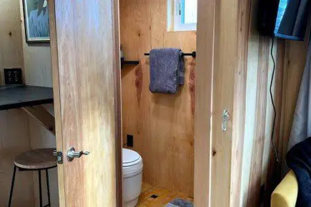 Compact modern bathroom with dual sinks, wood shelves, and black fixtures in Fairbanks Alaska rental
