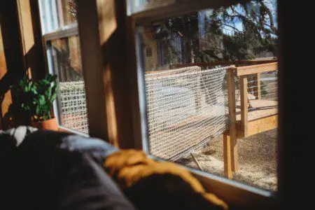 Comfortable gray couch with textured pillows and warm throw blanket by sunlit windows in a Fairbanks Alaska rental