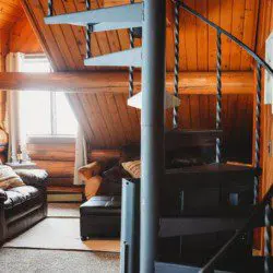 Cozy leather seating and warm wood interior of a Fairbanks treehouse rental with view into a small kitchen