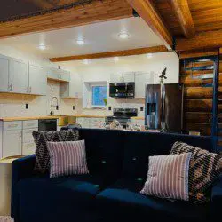Stylish kitchen with white cabinets and navy couch in a rustic Fairbanks Alaska treehouse rental