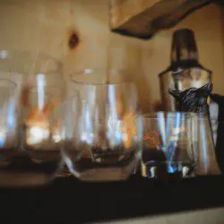 Compact treehouse kitchen with water dispenser, hanging pans, and soap near small sink in Fairbanks Alaska