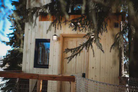 Wooden rope bridge leading to a cozy treehouse cabin among pine trees in Fairbanks Alaska