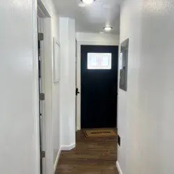 Bright hallway with wooden floors leading to black front door in Fairbanks Alaska rental