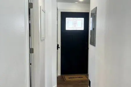 Bright hallway with wooden floors leading to black front door in Fairbanks Alaska rental