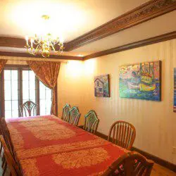 Classic dining room with a long red-covered table, chandelier, wooden chairs, and wall art in a Fairbanks Alaska lodge