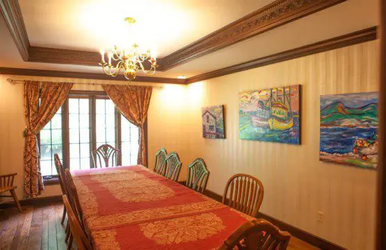 Classic dining room with a long red-covered table, chandelier, wooden chairs, and wall art in a Fairbanks Alaska lodge