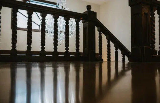 Wooden staircase with chandelier reflection on polished floor in a Fairbanks Alaska lodge or rental
