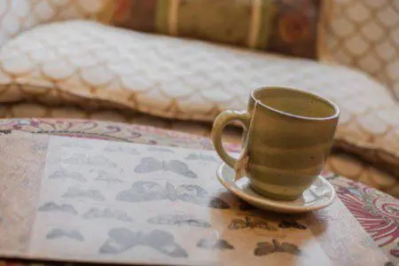 Close-up of a ceramic coffee cup on a butterfly print tray with patterned pillows in the background, Fairbanks Alaska
