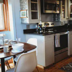 Kitchen with stainless appliances and dining table set for two in a Fairbanks Alaska treehouse