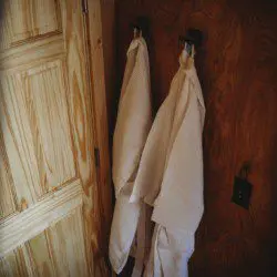 Two soft robes hanging on rustic hooks beside a wooden door in a Fairbanks Alaska treehouse