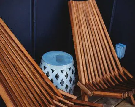 Two slatted wooden lounge chairs and a ceramic side table on a Fairbanks Alaska treehouse deck