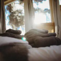 Sunlit Fairbanks Alaska treehouse bedroom with cozy towels—perfect for adventure lodge stays or wedding weekends.