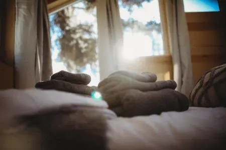 Sunlit Fairbanks Alaska treehouse bedroom with cozy towels—perfect for adventure lodge stays or wedding weekends.