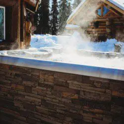 Steaming outdoor hot tub beside a log cabin in snowy Fairbanks Alaska
