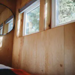 Wooden interior wall with windows and mirror inside a rustic Fairbanks Alaska treehouse