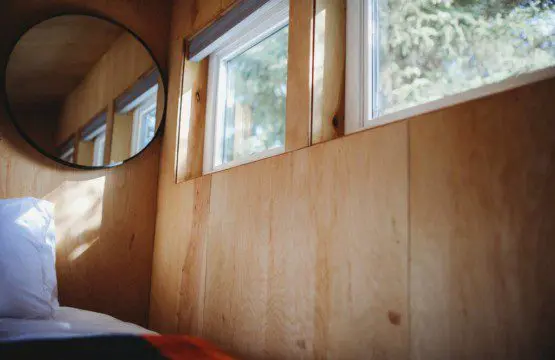 Wooden interior wall with windows and mirror inside a rustic Fairbanks Alaska treehouse