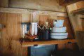 Wood shelf with plates, utensils, and blender in a cozy Fairbanks Alaska treehouse rental kitchen