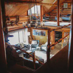 Warm wood-paneled lodge with log beams, loft seating, and cozy furniture in Fairbanks, Alaska
