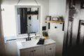 Cozy bathroom with wooden vanity, wall cross decor, and toilet in a Fairbanks Alaska lodge or treehouse rental
