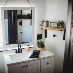 Cozy bathroom with wooden vanity, wall cross decor, and toilet in a Fairbanks Alaska lodge or treehouse rental