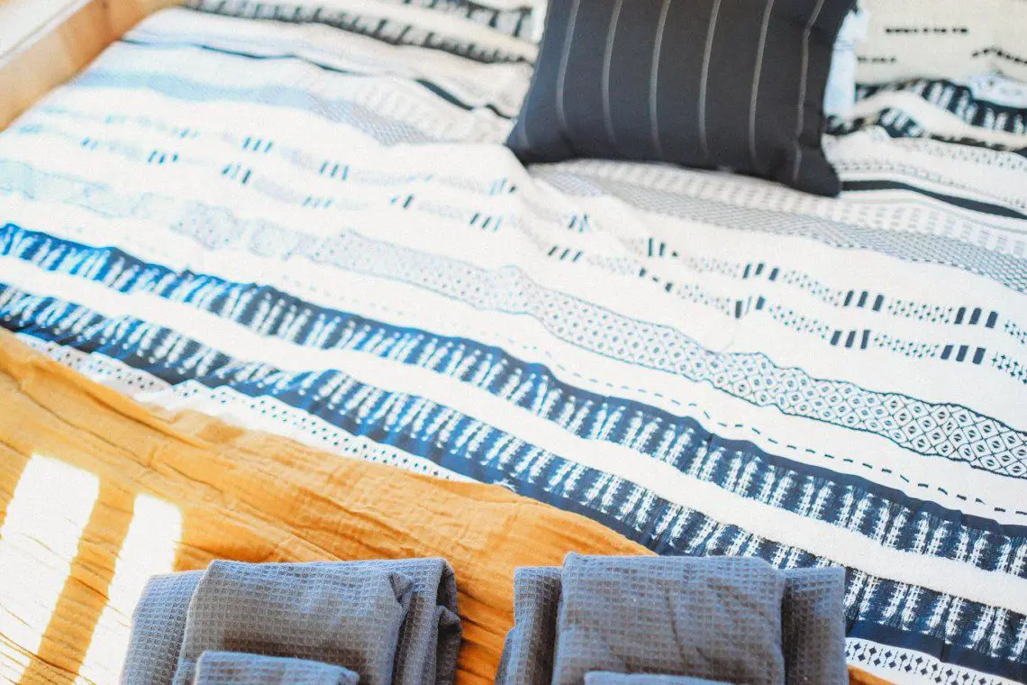 Colorful striped bedding with neatly folded towels and pillows in a Fairbanks Alaska treehouse rental