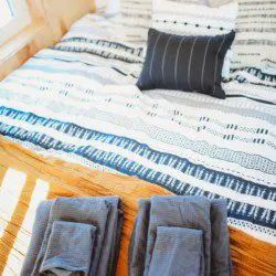 Colorful striped bedding with neatly folded towels and pillows in a Fairbanks Alaska treehouse rental