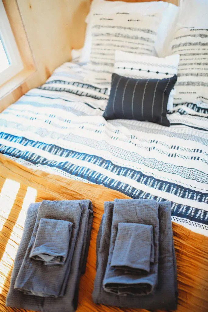 Colorful striped bedding with neatly folded towels and pillows in a Fairbanks Alaska treehouse rental