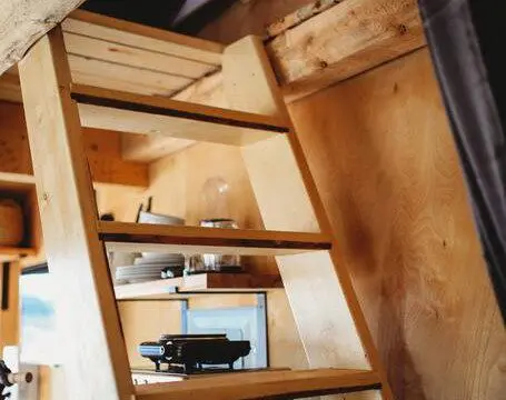 View looking down wooden stairs from a loft inside a Fairbanks Alaska treehouse rental