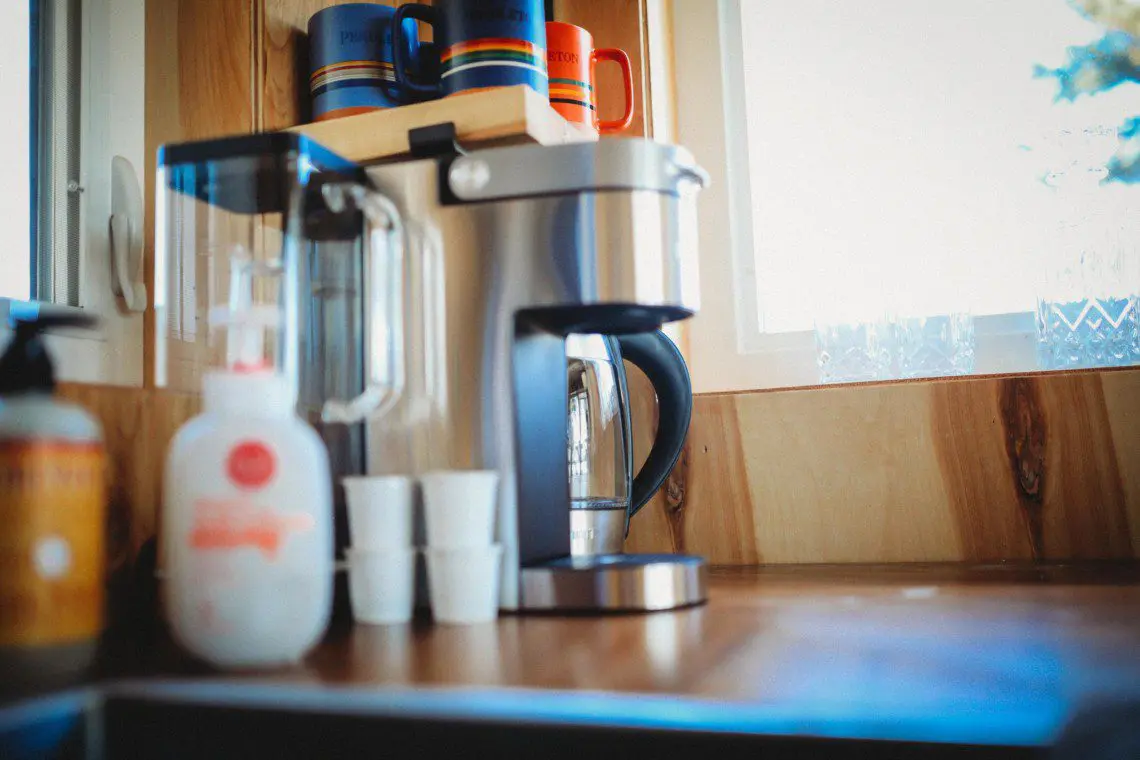 Coffee maker with mugs and cups on a wooden counter near a window in a Fairbanks Alaska treehouse