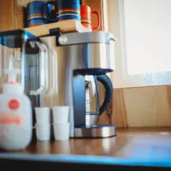 Coffee maker with mugs and cups on a wooden counter near a window in a Fairbanks Alaska treehouse