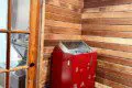 Wood-paneled sauna room with red heater and glass door in a Fairbanks Alaska adventure lodge