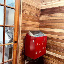 Wood-paneled sauna room with red heater and glass door in a Fairbanks Alaska adventure lodge