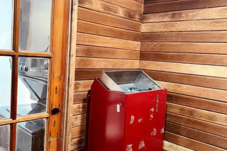 Wood-paneled sauna room with red heater and glass door in a Fairbanks Alaska adventure lodge
