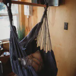 Indoor hanging hammock chair with pillow in a wood-paneled room of a Fairbanks Alaska treehouse rental