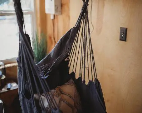 Indoor hanging hammock chair with pillow in a wood-paneled room of a Fairbanks Alaska treehouse rental