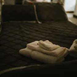 Freshly folded towels on a dark quilted bed in a cozy Fairbanks Alaska adventure treehouse