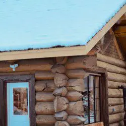 Rustic log cabin with blue door and snow-covered roof in Fairbanks Alaska
