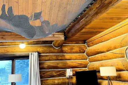 Living room with log walls and ceiling hammock net in a Fairbanks Alaska treehouse rental